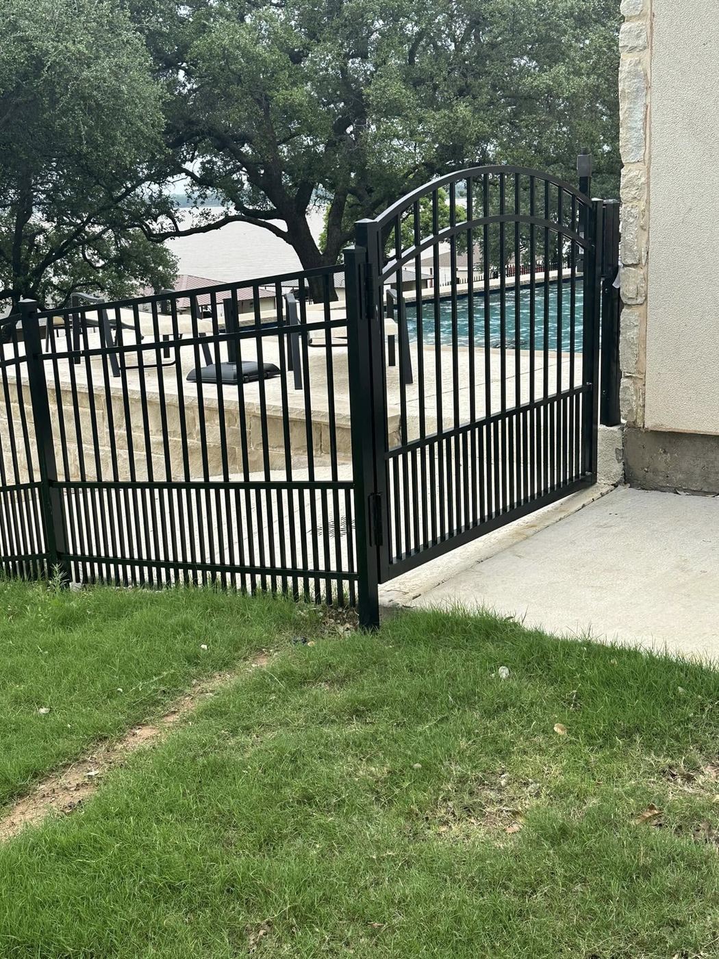 Arched iron pool gate with a lake view