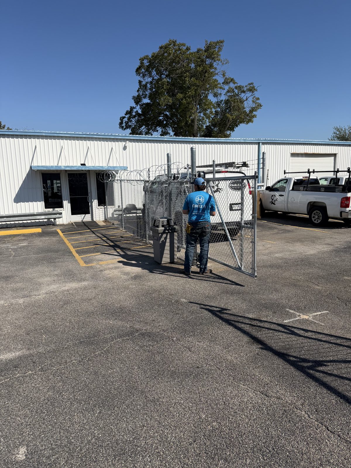 Circle H crew member installing a chain link gate at a commercial building