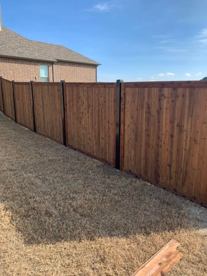 Wood privacy fence with black metal posts beside a brick house