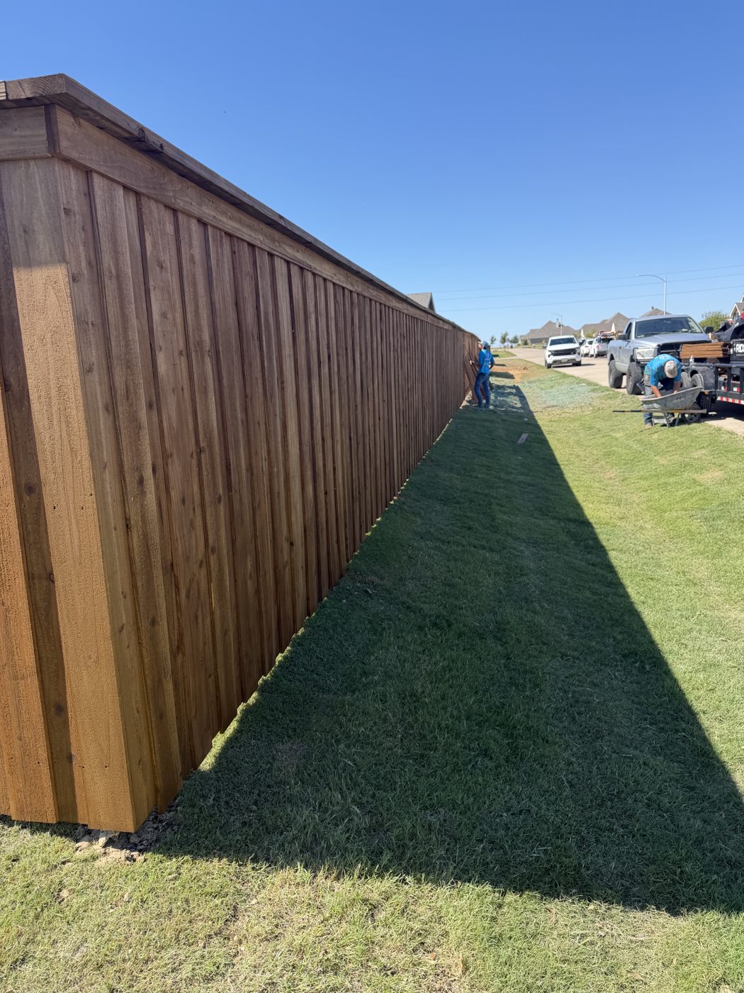 Crew installing a long wood privacy fence line