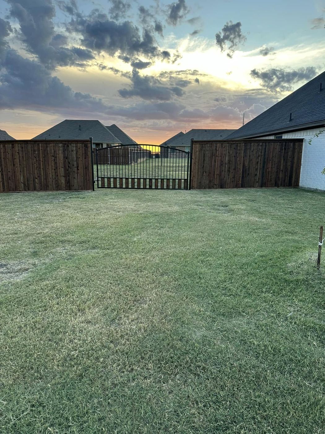 Wood fence with an arched wood and iron gate at sunset