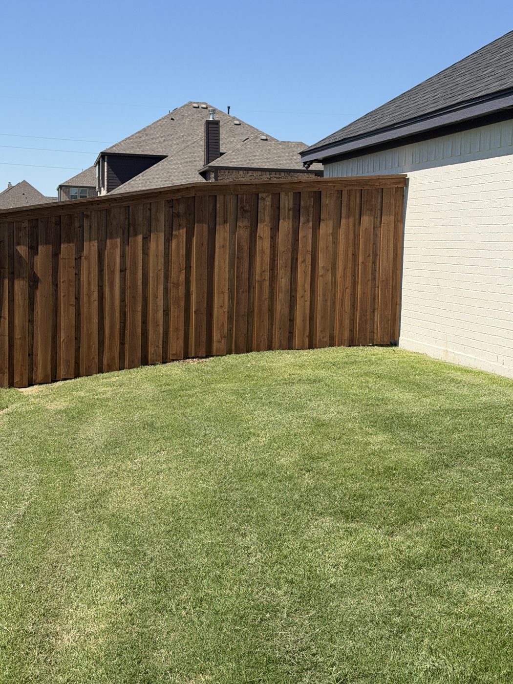 Wood privacy fence corner beside a brick home