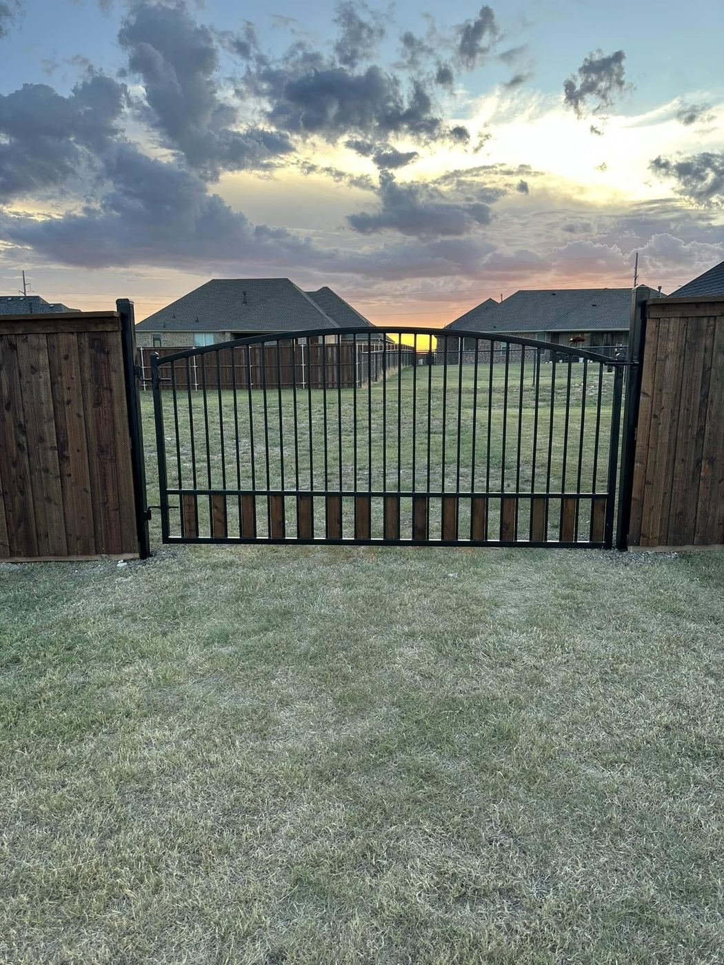 Custom wood and iron arched gate at sunset